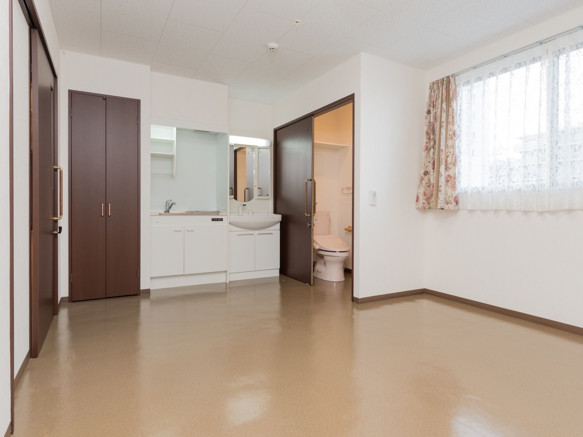 居室には大きな窓があり、自然な光が差し込み、又外の景色を楽しめる。洗面台やキッチンが作り付けになっている。
