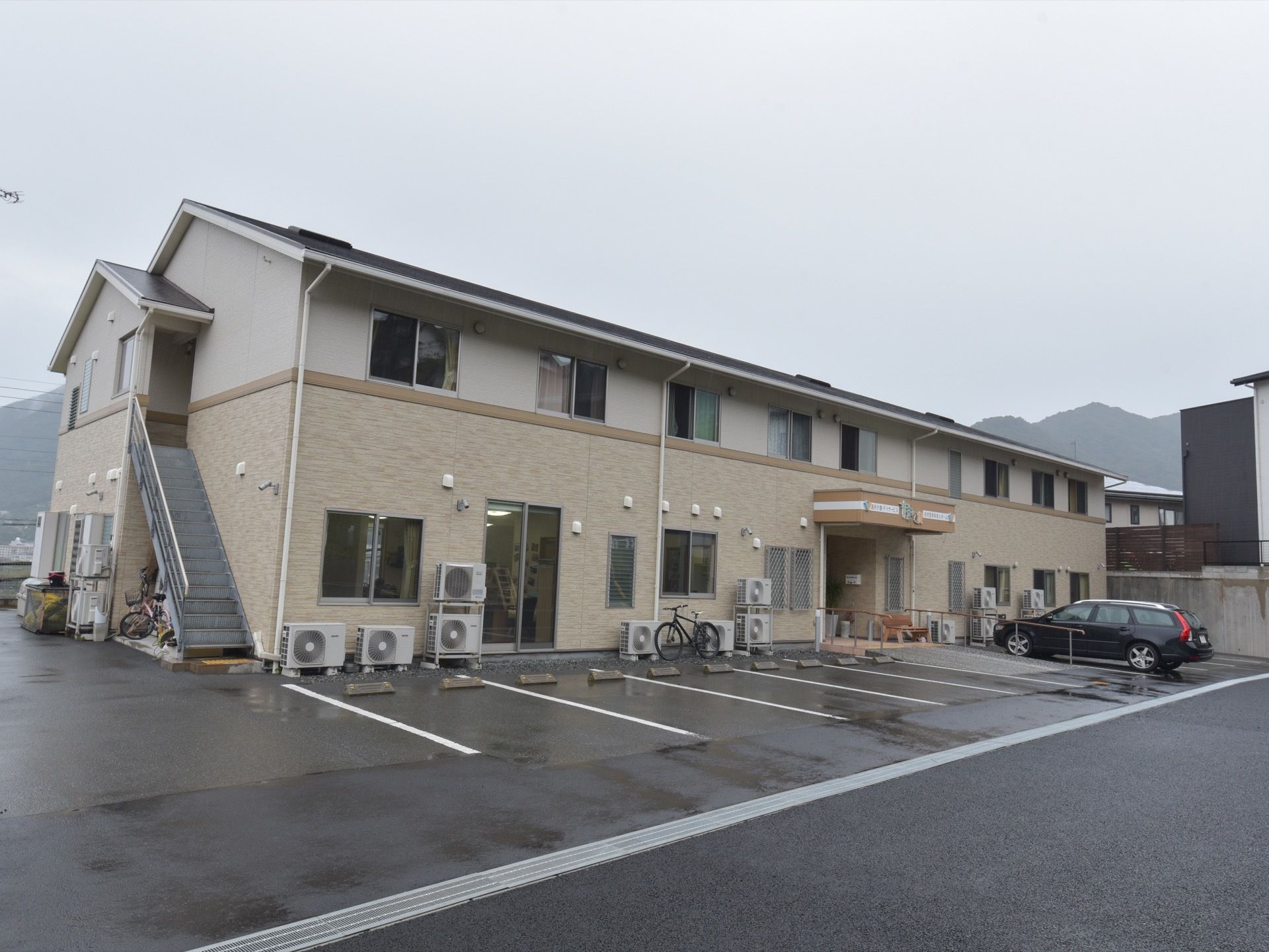 道路に面し、広々とした敷地に立地している２階建ての施設の外観。敷地内の駐車スペースから玄関までバリアフリー仕様になっている。