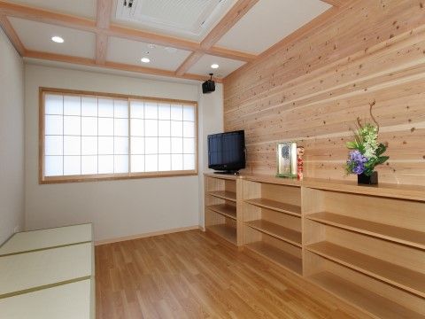 和室タイプの共有スペースが用意されている。壁に３段の棚があり、花瓶の生け花が飾られている。液晶テレビが置かれている。