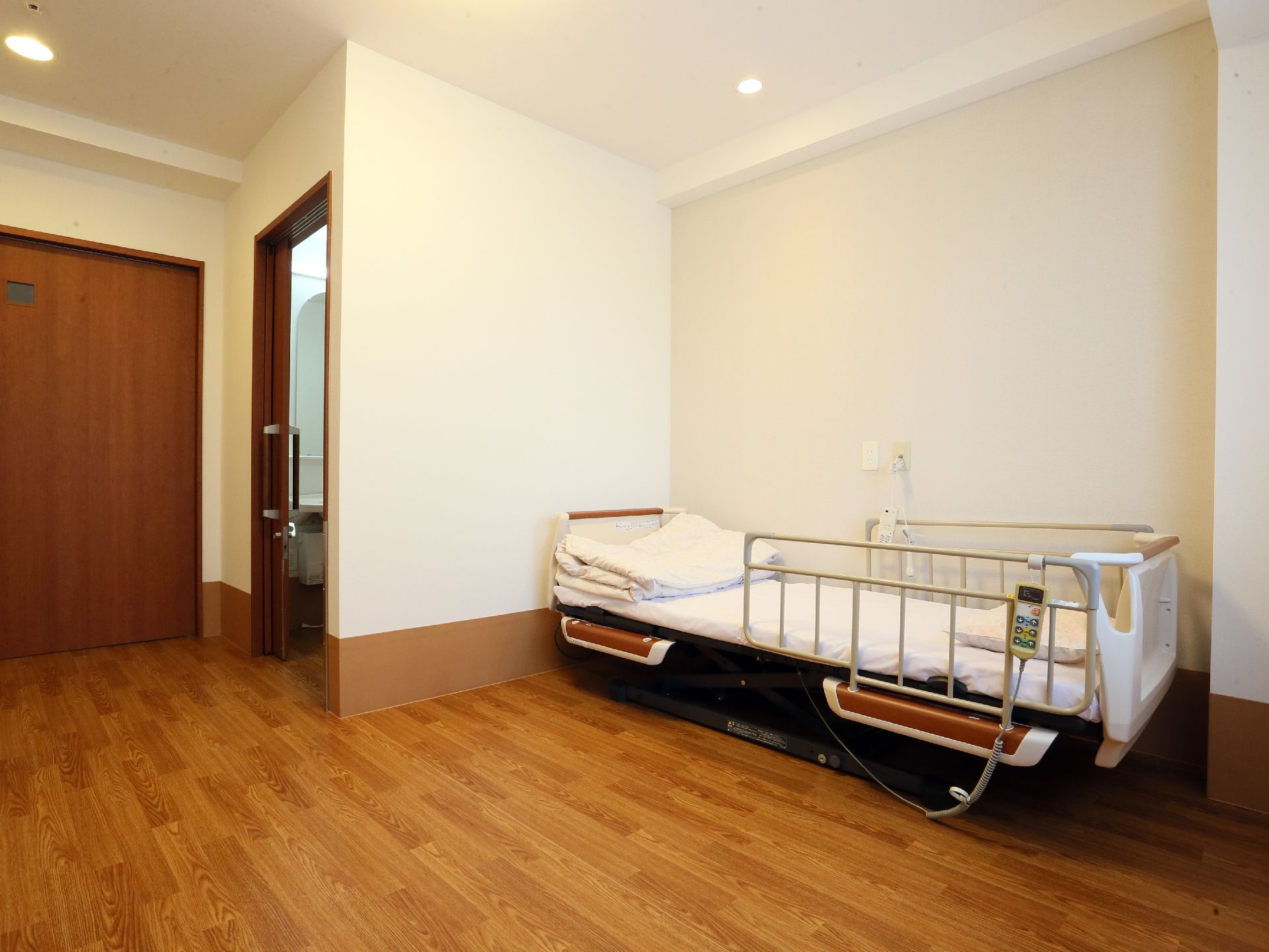 十分な広さのある居室には介護用ベッドが置かれている。洗面台スペースとトイレが室内に付いているタイプの部屋もある。