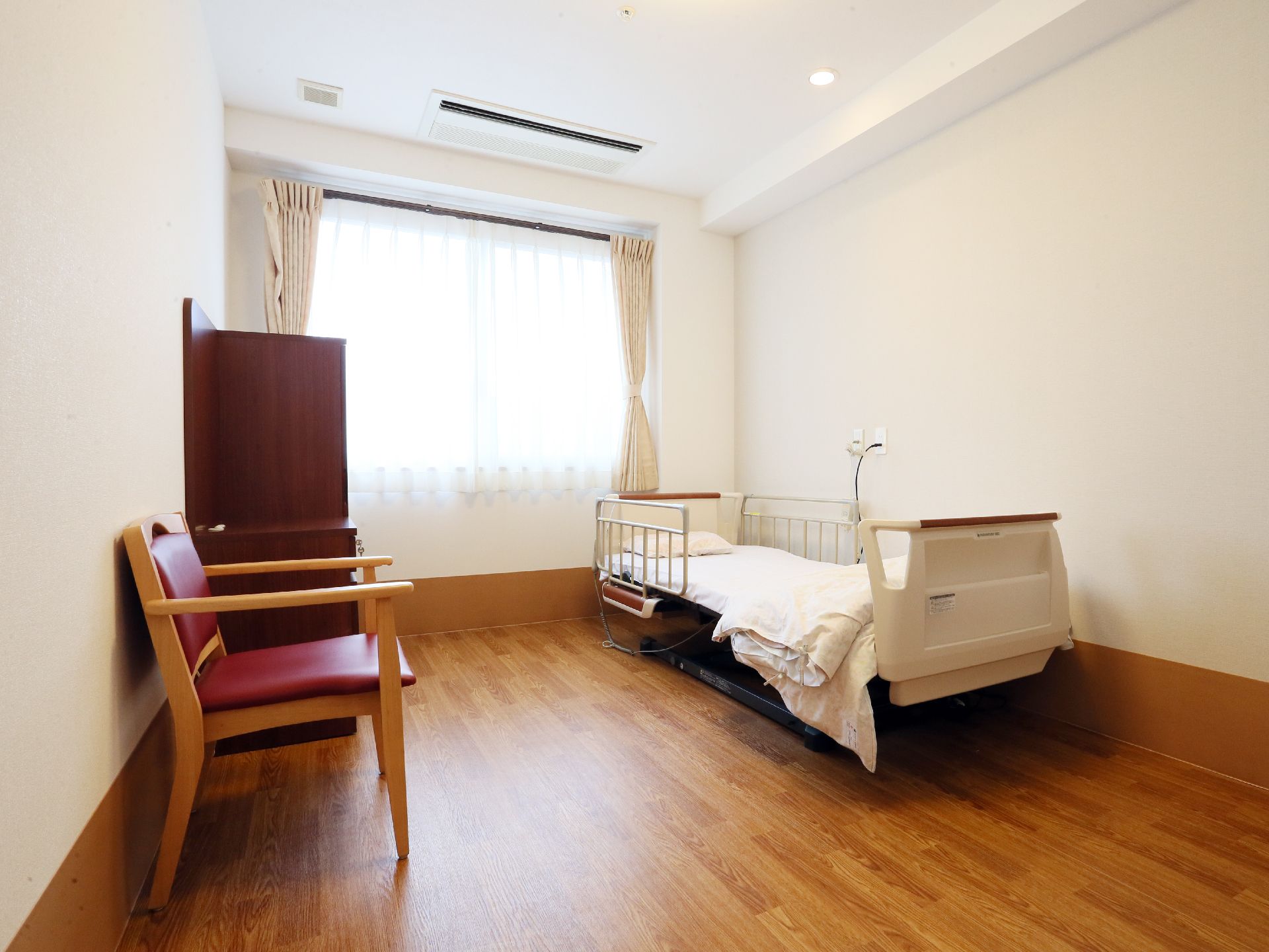 個室には介護用電動ベッド、収納キャビネット、椅子が備わっている。家具が置いてあっても余裕を持った部屋の作りである。