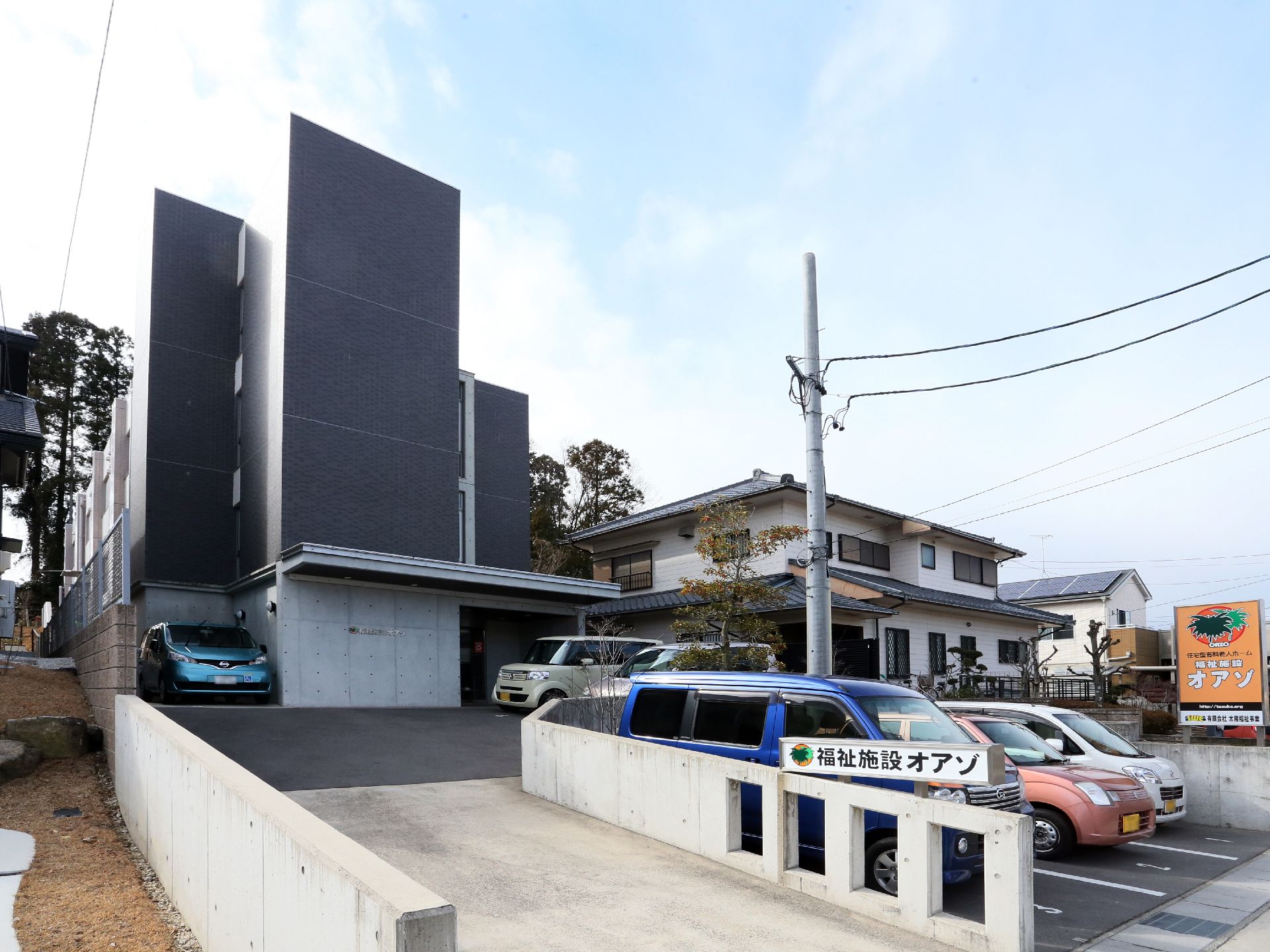 ３階建ての建物は、黒と白に塗り分けられたモダンなデザインの外観になっている。玄関ポーチ前には駐車スペースがある。
