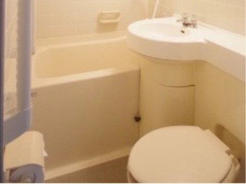 居室にある、お風呂とトイレと洗面台が一体になっているタイプのユニットバス。トイレの前の壁には手すりが設置されている。