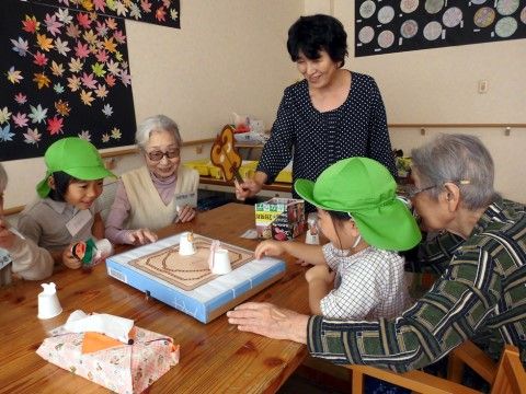 テーブルを囲んで、トントン相撲を楽しむ入居者様と園児