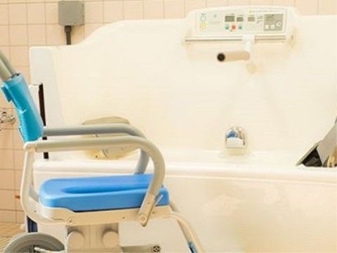 座ったままの姿勢で入浴することができる設備が備わっている。隅々まで磨かれた浴槽である。浴室専用の車椅子が置かれている。