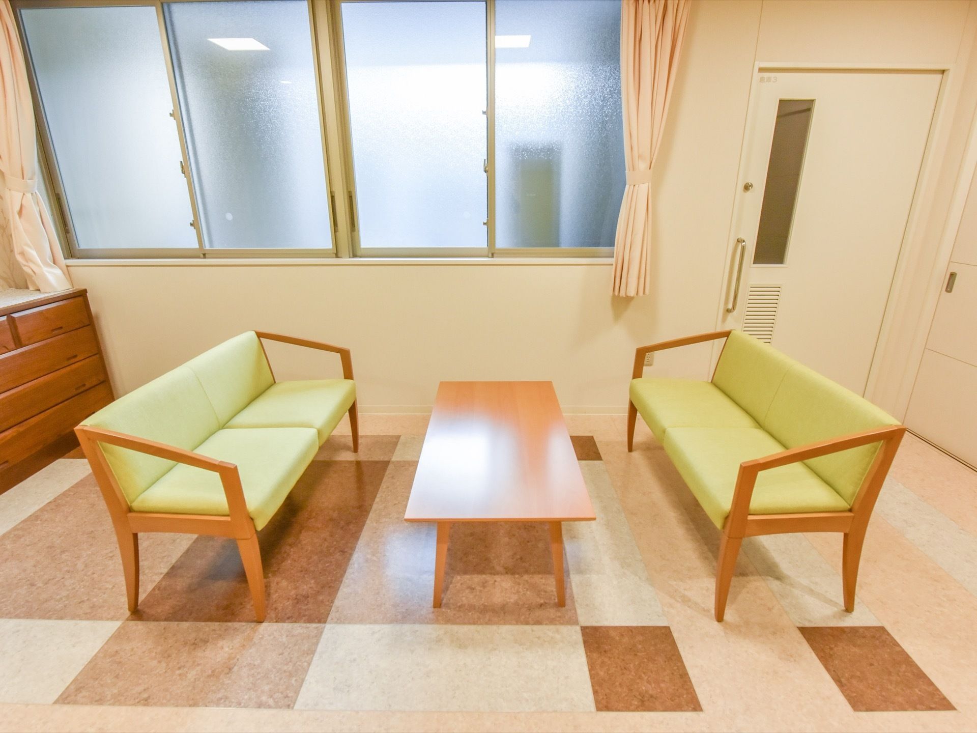 ソファとテーブル、チェストが置かれている。壁の奥には部屋があり、窓とドアが付いている。床はベージュや茶色などで模様が入っている。