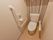 手すりや緊急呼び出しブザーの設置された、温水洗浄便座のトイレである。後方の壁紙はストライプ模様である。