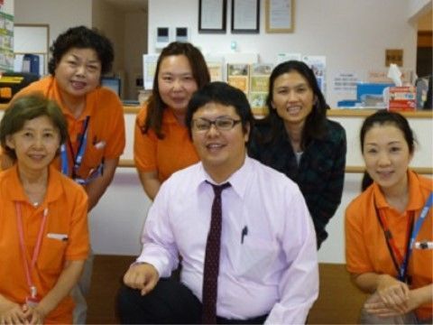 事務室のカウンター前で、笑顔で写真に写る６人のスタッフ
