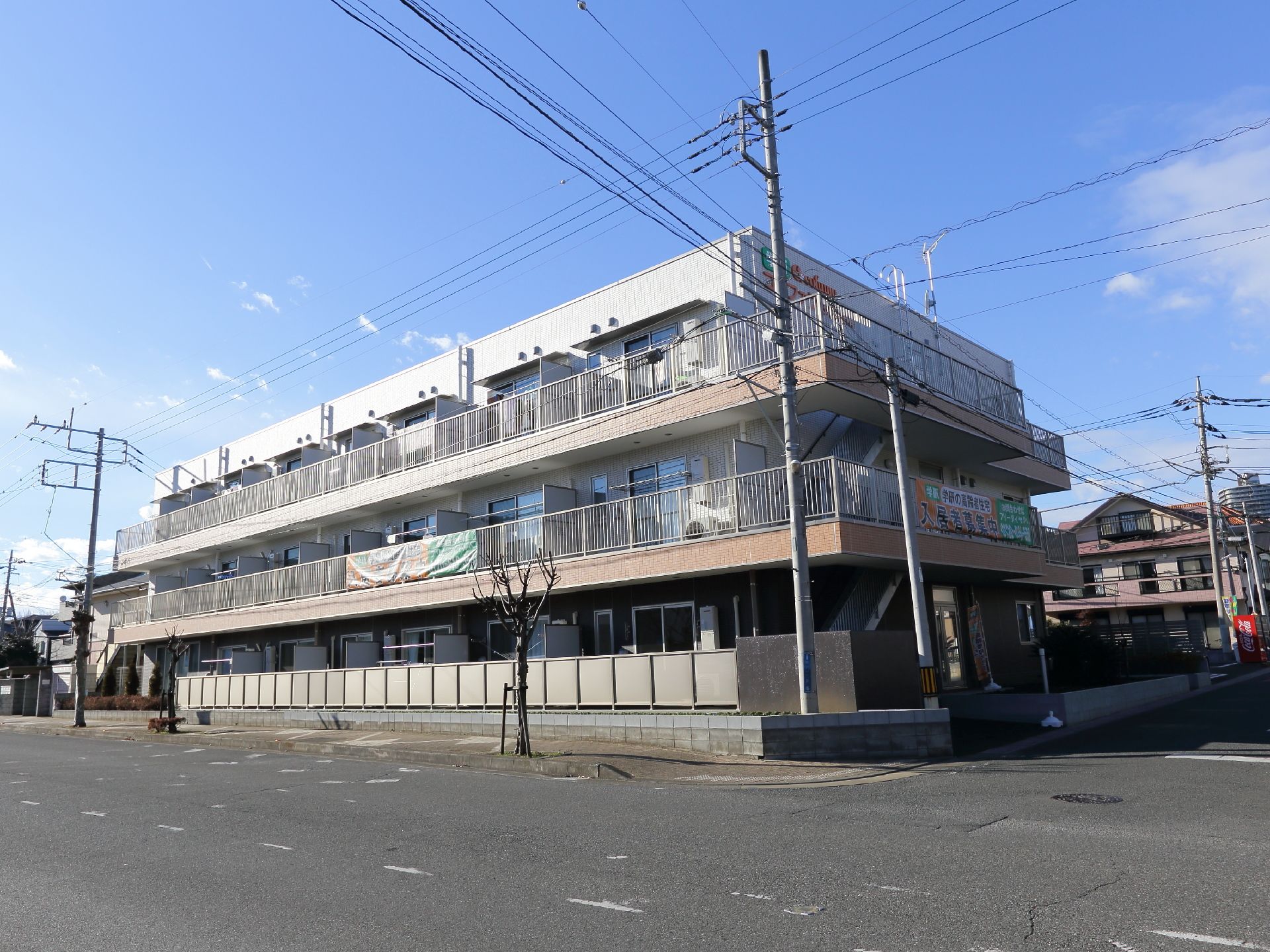 "建物は道路に面している。建物は3階建てになっている。1階～3階までベランダが付いている。右側には外階段が付いている。"
