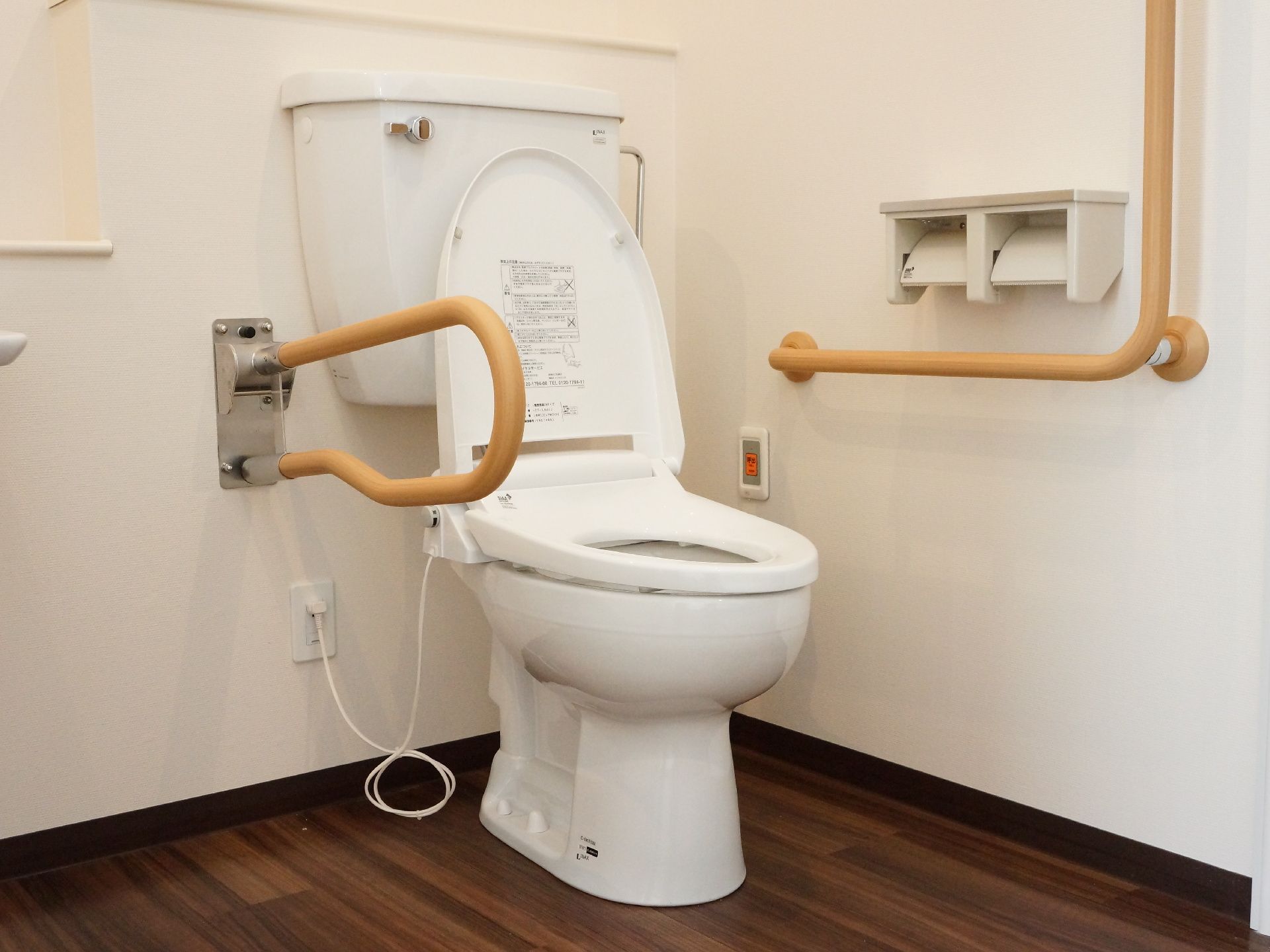 居室のトイレは、ウォッシュレット。両脇に手すりが設置されており、緊急ボタンもすぐ横についているので安心。