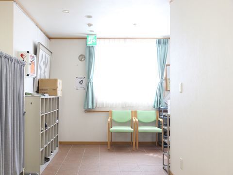 靴箱やひじ掛け付きの椅子が設置されている、明るいエントランス