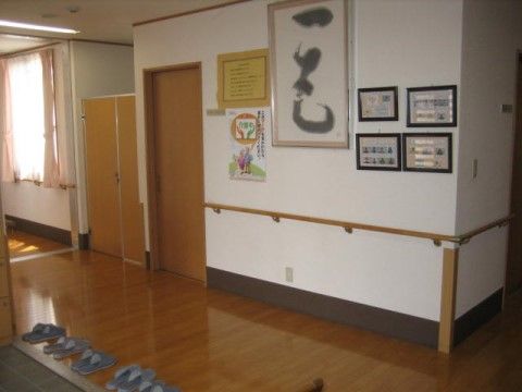 壁に手すりが設置されている、床がフローリングの廊下