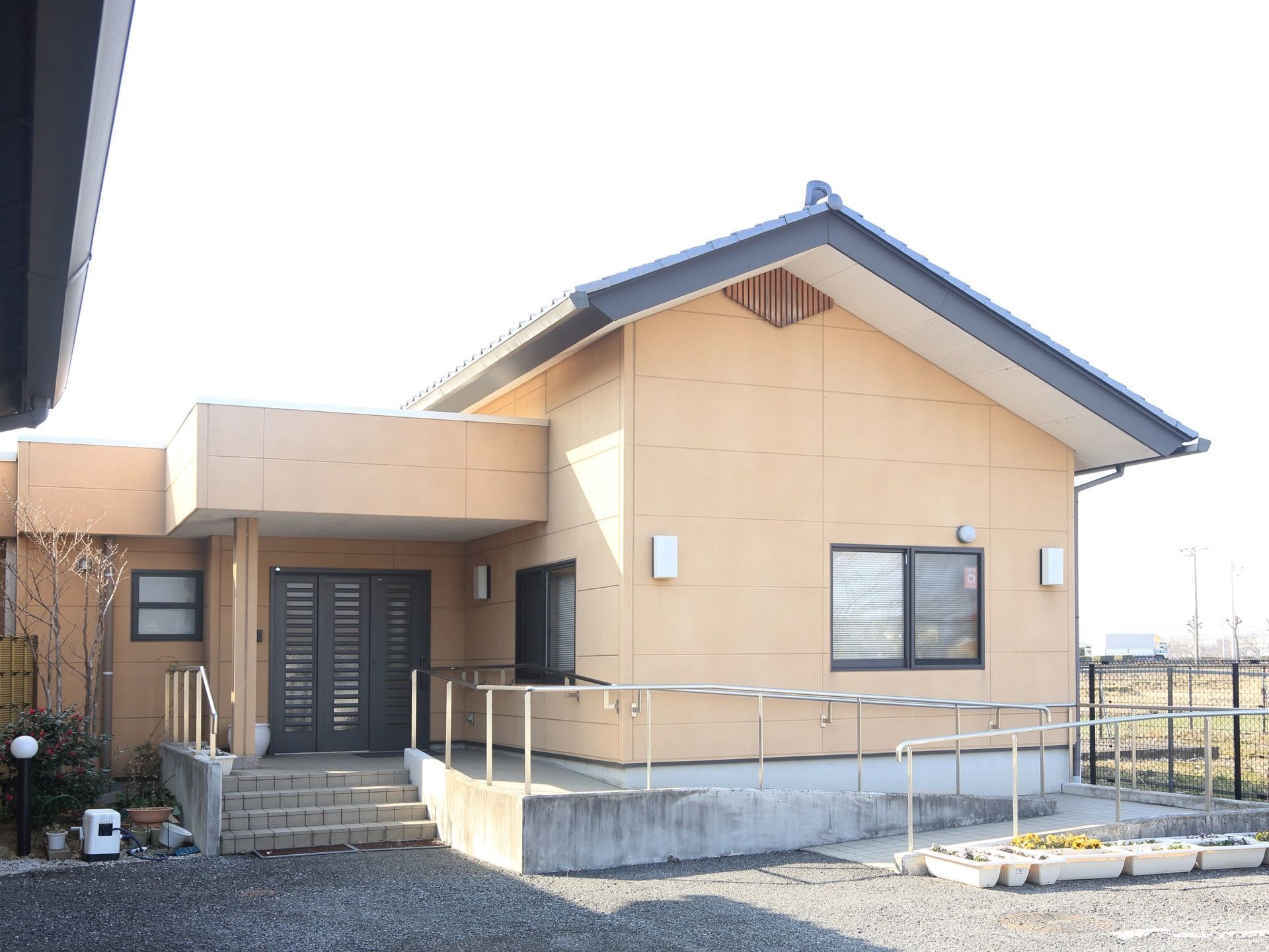 民家を思わせるような三角屋根の建物である。エントランスまでは緩やかな階段が完備され、手すりがあるので安全に歩行ができる。