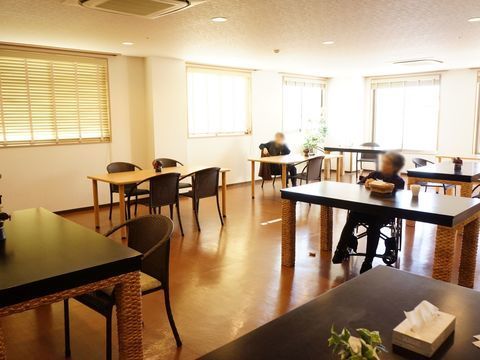 たくさんの窓があるリビングで、椅子に座って寛ぐ入居者様