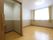 居室のトイレは引き戸になっている。トイレの奥にフローリングの居住スペースが広がり、大きな窓にカーテンが掛けられている。