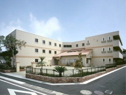 住宅街の角に立つ、白を基調とした大きな３階建ての建物