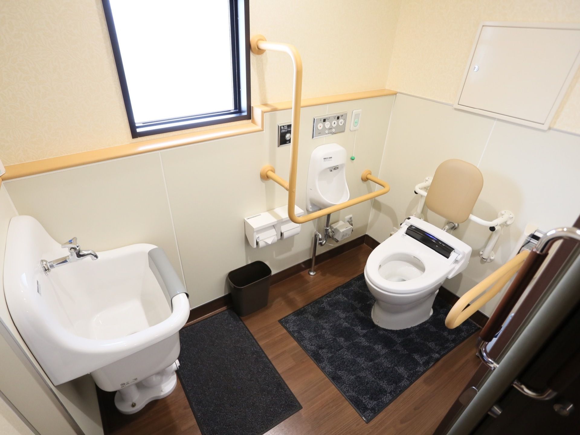 トイレの便座の周りには、手すりが数多く設置されている。窓があり、換気をすることができる。深めのシンクも設置されている。
