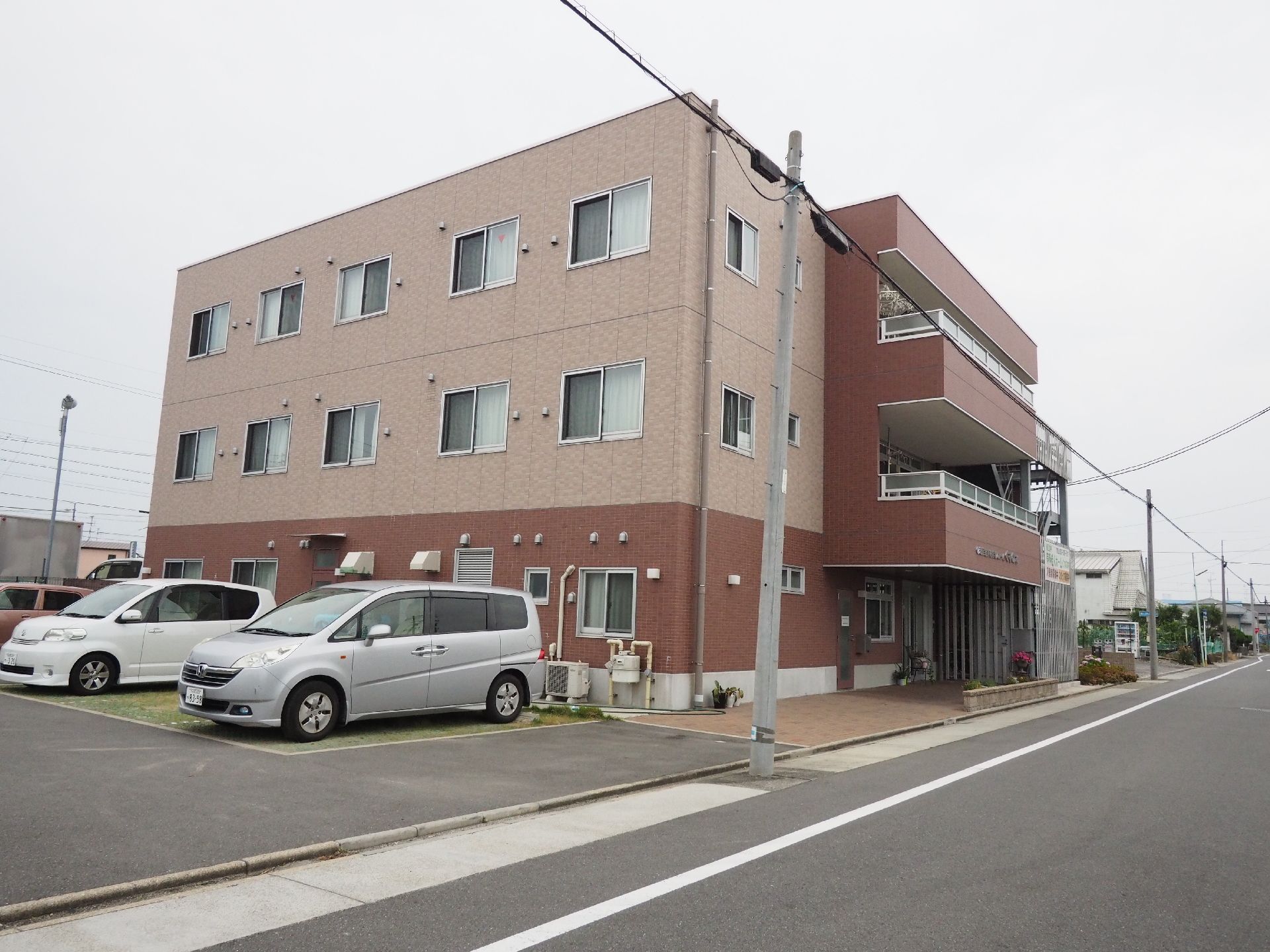 マンションのような外観で、色合いも落ち着いている。駐車場がすぐ側にあるので、建物への移動距離が短くなっている。