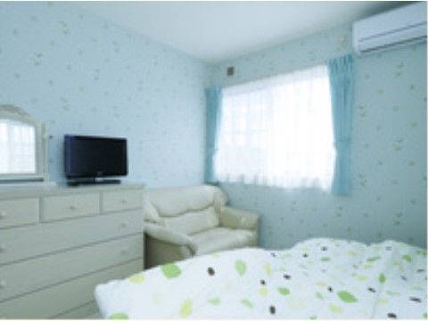 ベッドシーツと壁紙が同じ柄が使われ、室内は統一されたデザインになっている。壁には、エアコンが設置されている。