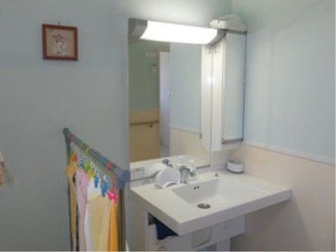 洗面台の足元は広々としており、車椅子をご利用の方でも安全に使用できる。鏡は大きく、横に収納スペースがある。