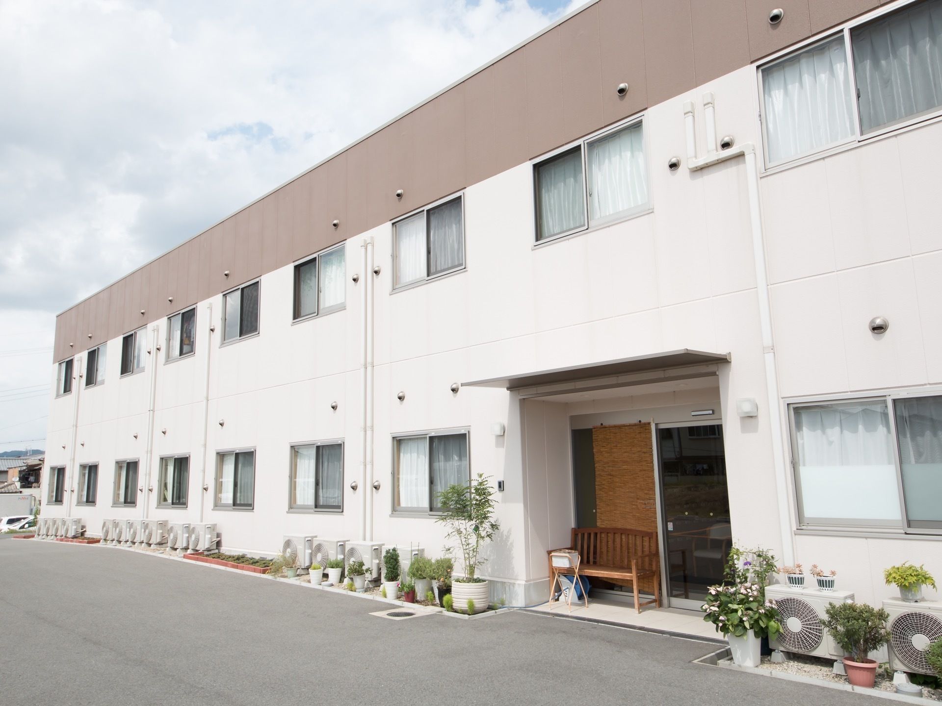 ガラス張りの自動ドアの横にベンチが設置されている玄関