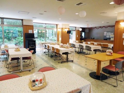 一面がガラス窓の大きな部屋。窓に向かって右手奥にはカウンターがある。石張りの床の上にはゆったりと間隔をあけてダイニングセットが並んでいる。