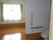窓から明るい光の差し込み、磨かれた床が照らされている居室。手前にはトイレがあり、手すりが設置されている。