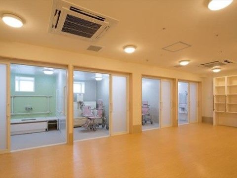 脱衣所から４つのドアに分かれた浴室に入ることができる。ドア内には、浴室用の車椅子や、手すりが付いた浴槽が見えている。