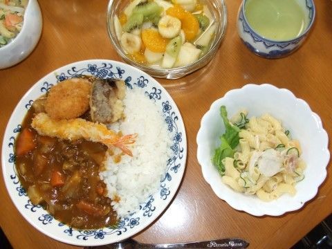 エビのフライが乗ったカレーライス。マカロニサラダとフルーツの盛り合わせ。