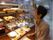 施設で開催される食のイベントでは、お店に行って女性の入居者様がトレーにトングを使ってドーナッツを取っている。