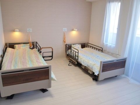 ベッドを２台設置した、２人で入居することができる居室である。窓から光が差し込む清潔感のあるスペースである。