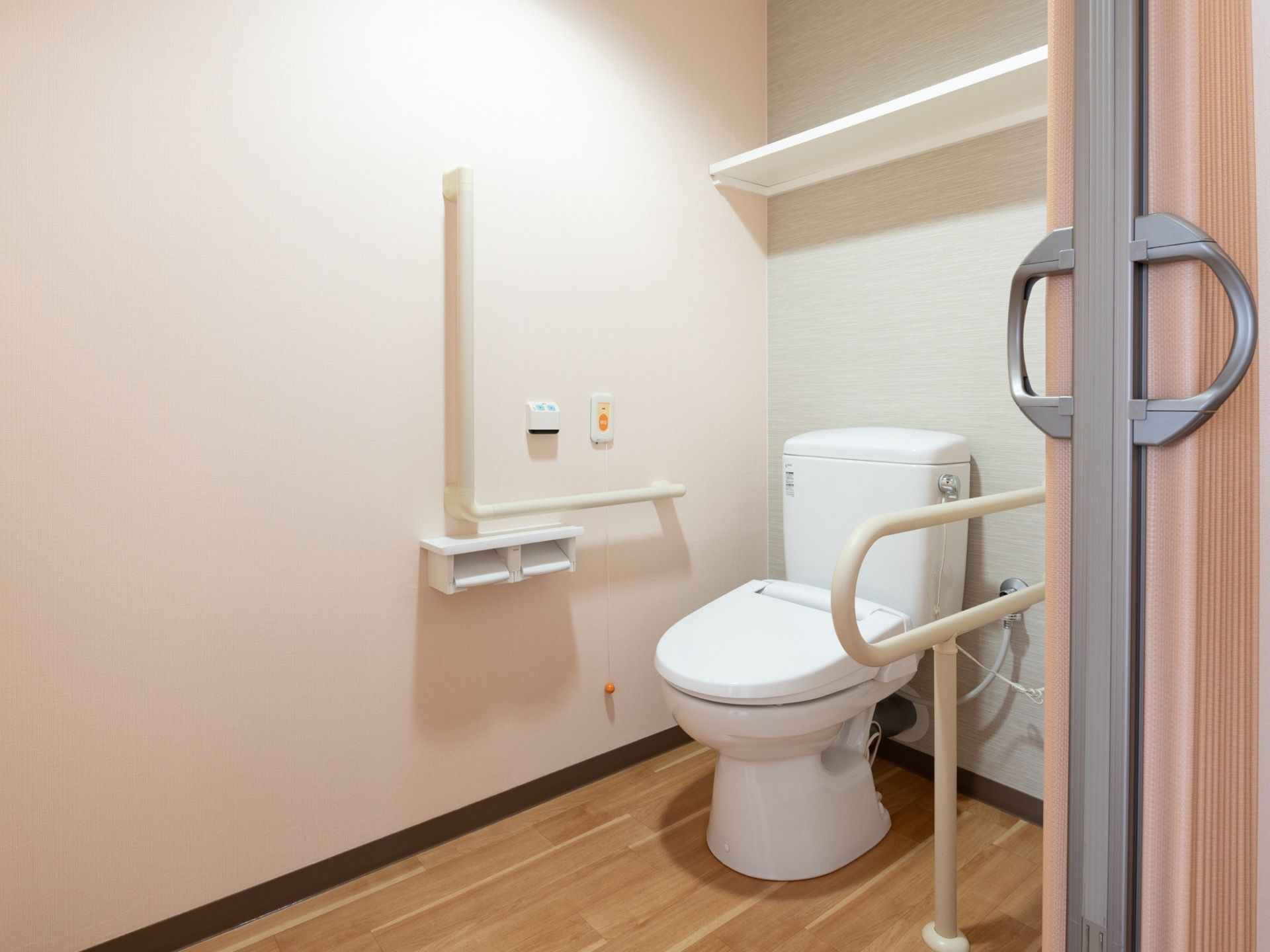 居室にトイレが設置されている。横スライド式のドアで広さも備わっている。壁には、手すりやナースコールも用意されている。