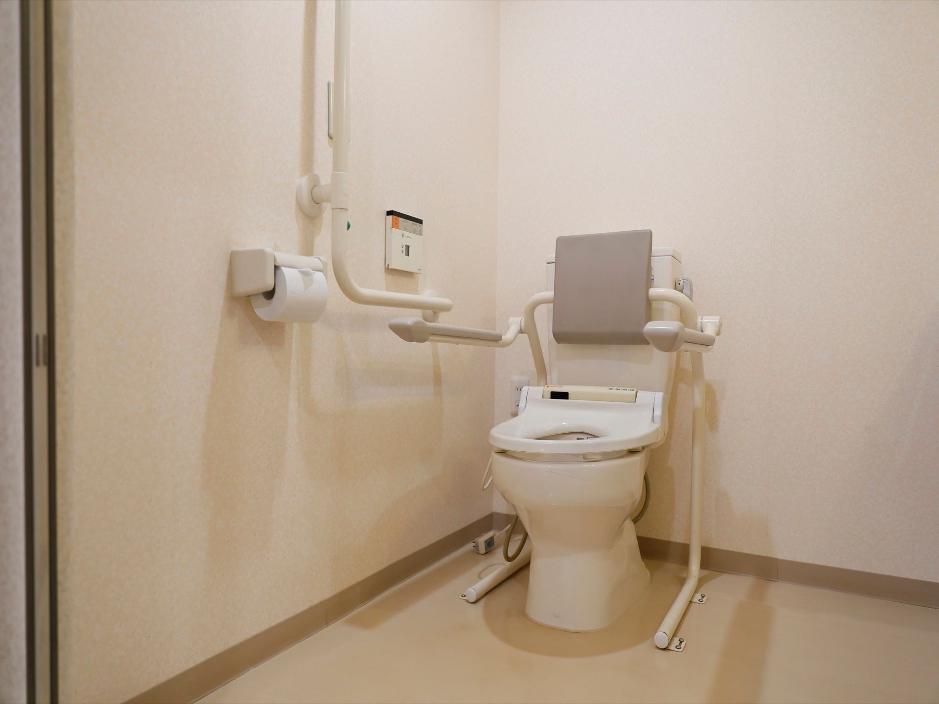 トイレは広く、スペースに余裕がある。背もたれやひじ掛けがついており、便座脇には大きな手すりがついている。
