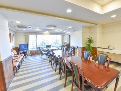 白と水色の縞模様の床にテーブルが長くつなげてセットされた食堂