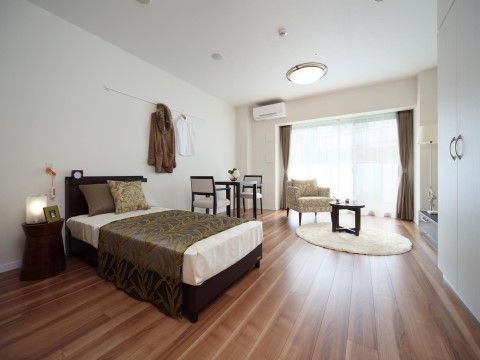 大きな窓がある居室。ベッドが１台、壁にはクローゼットが備え付けられている。ソファとミニテーブルが置かれている。