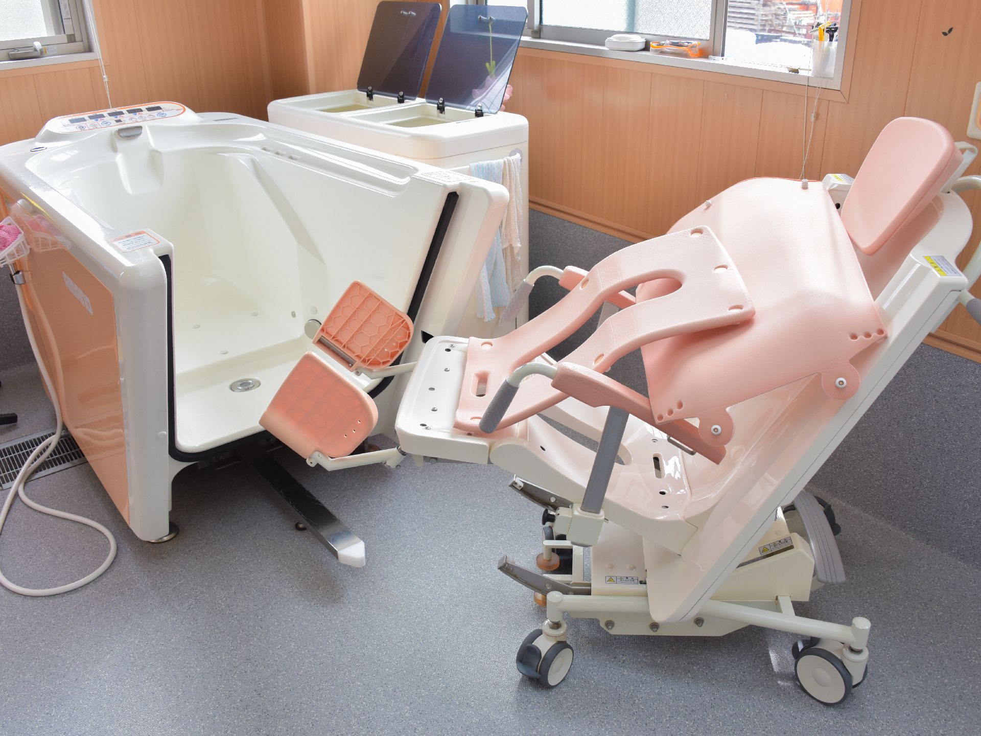 フラットなフロアに入浴用をサポートする設備が置かれている。キャスター付きの椅子に座り、バスタブにそのまま入れるようになっている。