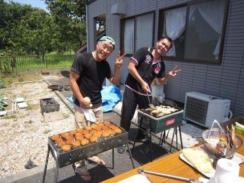 手前にテーブル、中央にバーベキューグリルを2つ並べて調理している2人のスタッフ