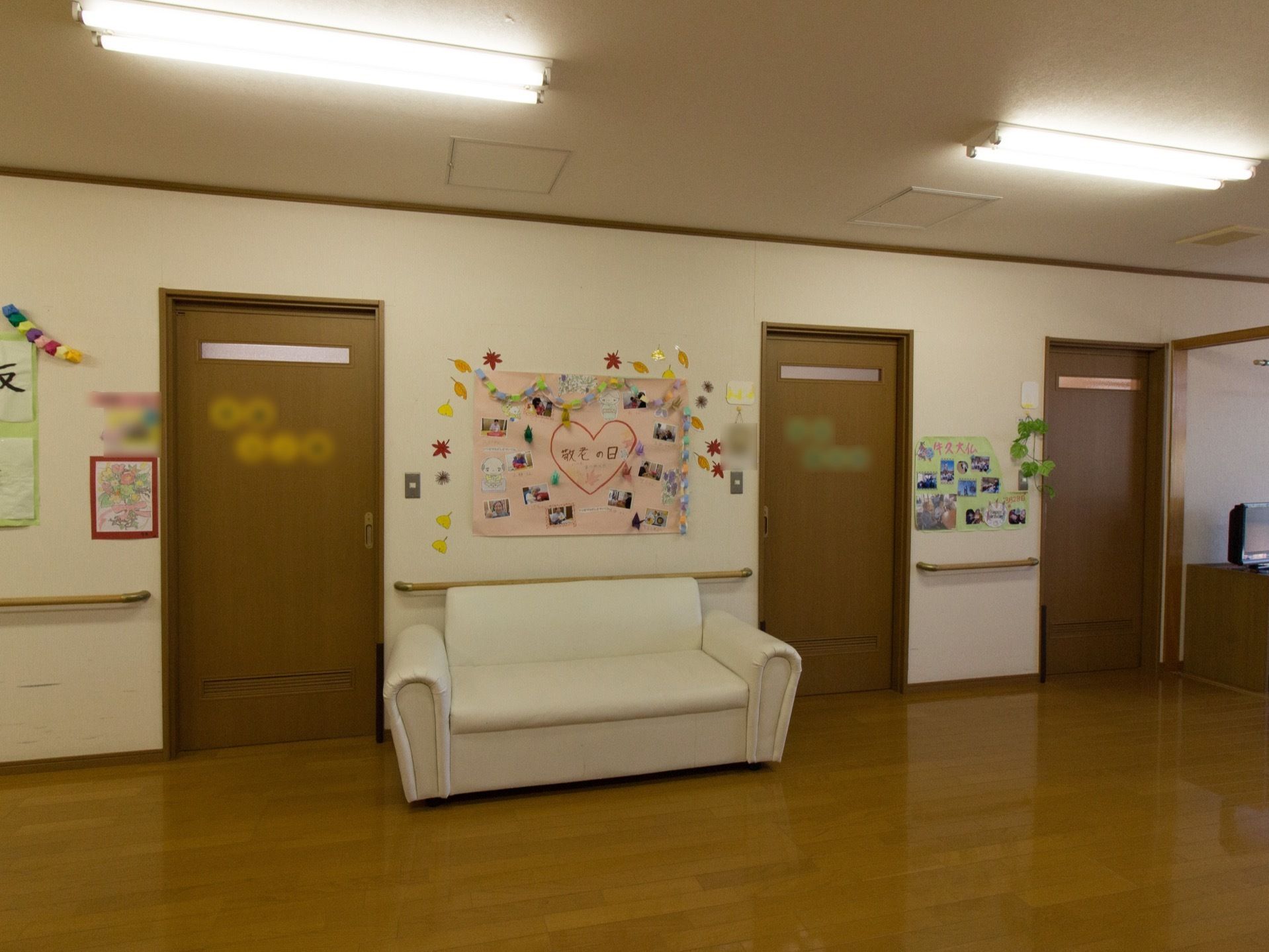 食堂兼リビングの壁際に、白いソファーが置いてある。敬老の日と書かれたピンクの画用紙に、たくさんの写真が貼ってある。