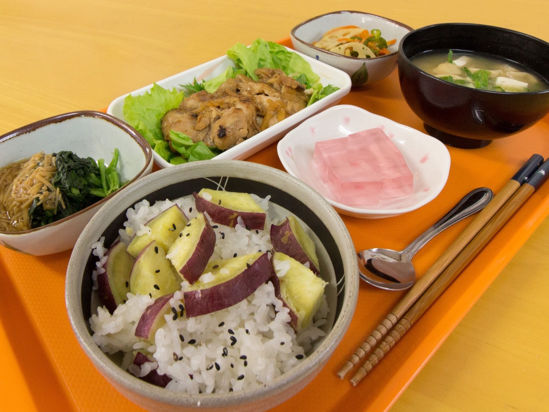 種類豊富な野菜が使われたお食事である。さつまいもご飯やみそ汁、おかずやデザートのゼリーが並べられている。