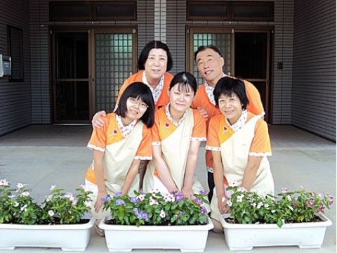 プランターの並んだポーチで寄り添っている5人のスタッフ