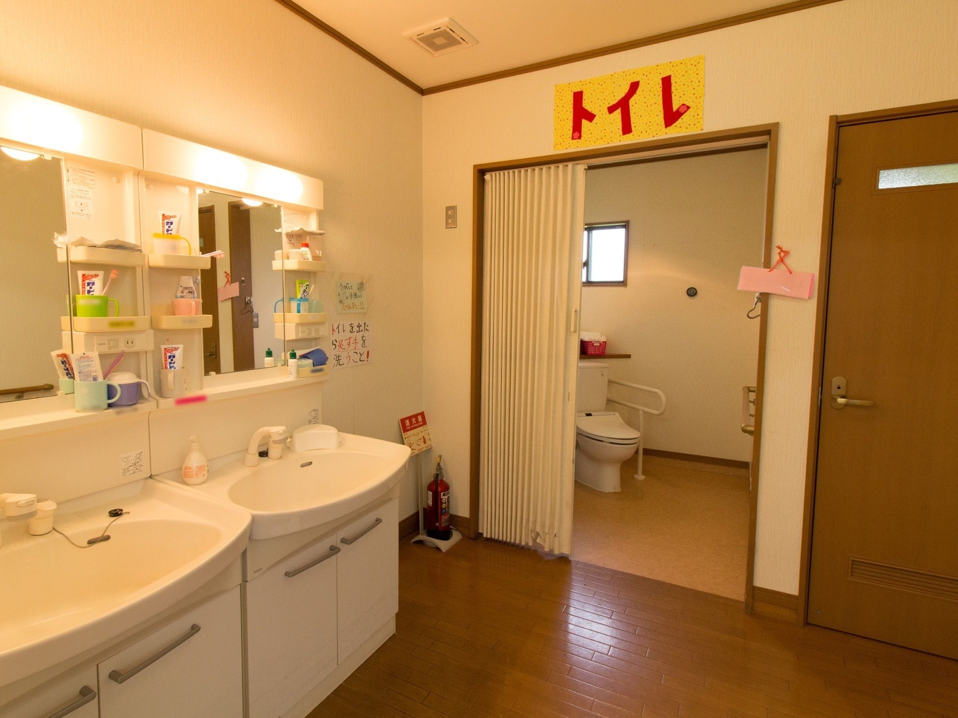 トイレはカーテンで仕切られたスペースに設置されている。洗面台が２セットある。緊急時用の消火器も置いてある。