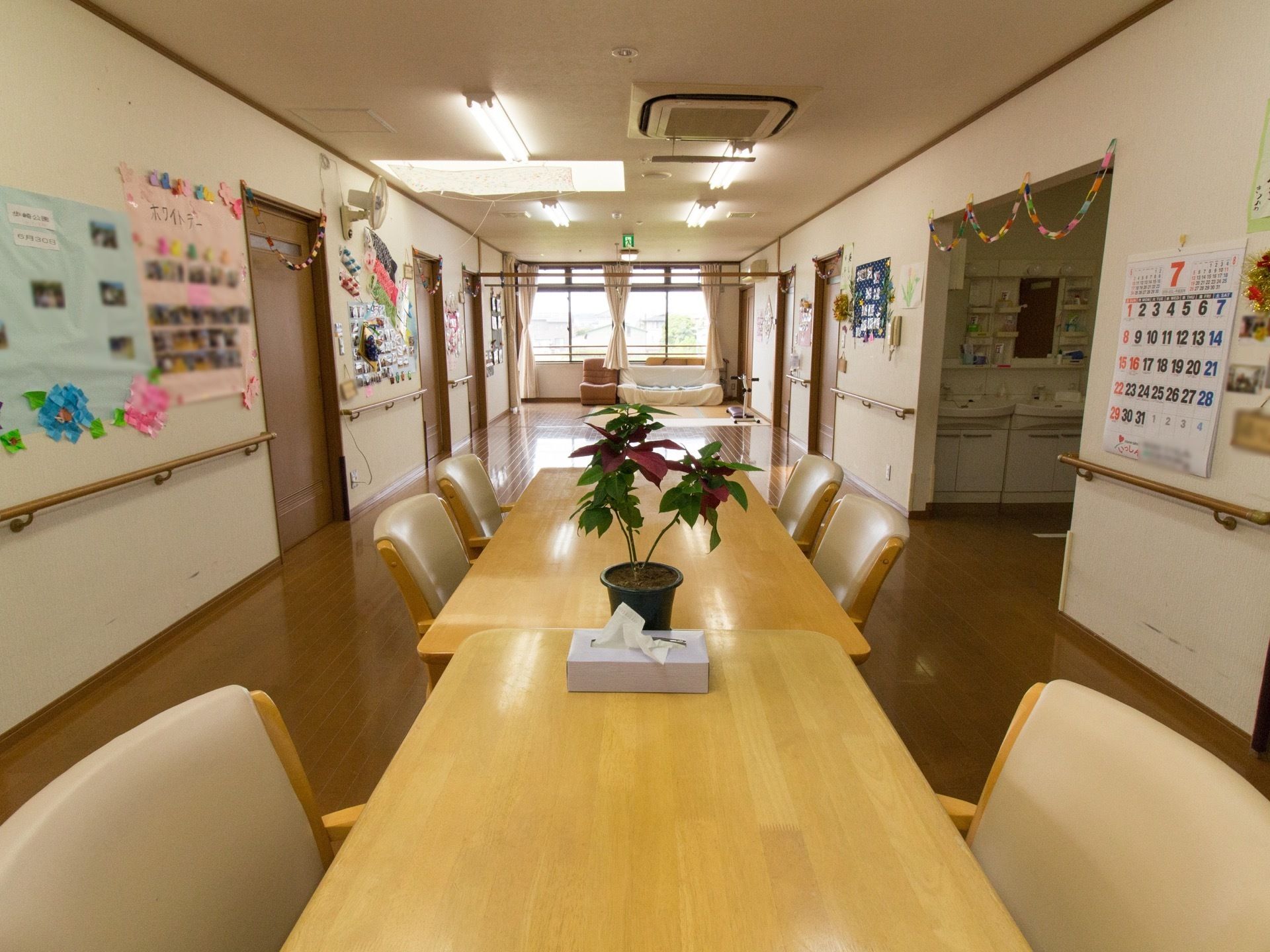 居室を出てすぐの場所が共有スペースになっている。施設のイベントの写真や、創作品などが壁面に飾られている。