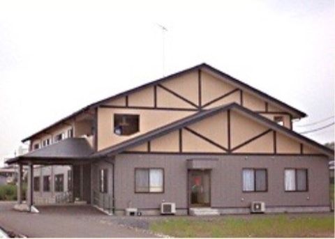 1階はあずき色、2階は淡いオレンジの壁で切妻屋根の2階建ての建物
