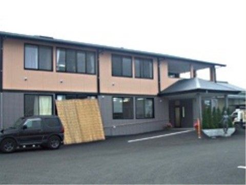 中央から右端にある玄関に向かってスロープがあり、1階にすだれが掛けてある建物