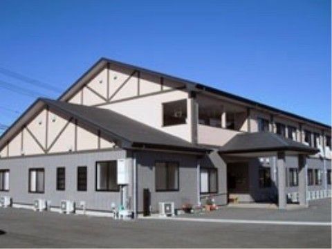 青空を背景にして2階にひさしのかかったベランダが続いている2階建ての建物