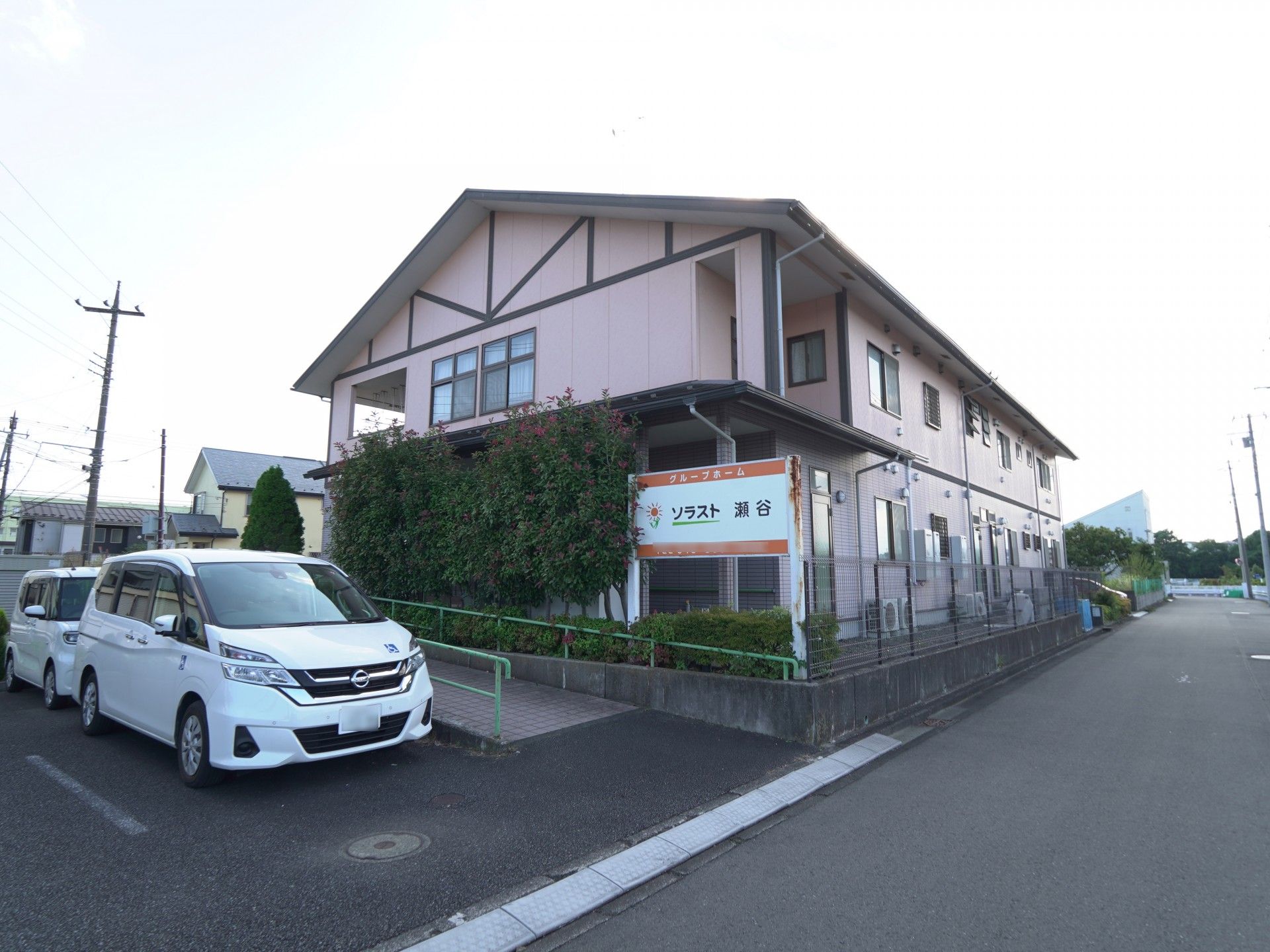 建物前の駐車場に車が2台とまっている外観