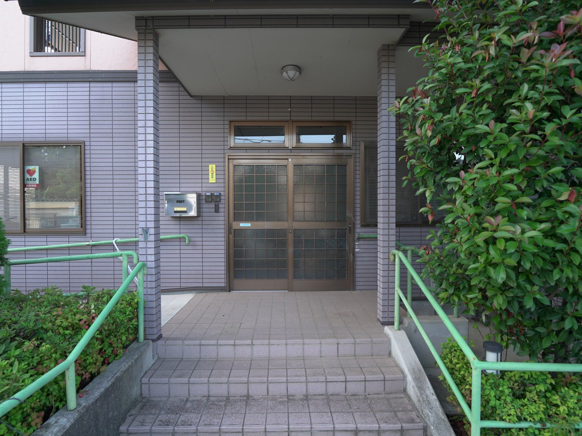 緑の手すりがある階段と建物入り口