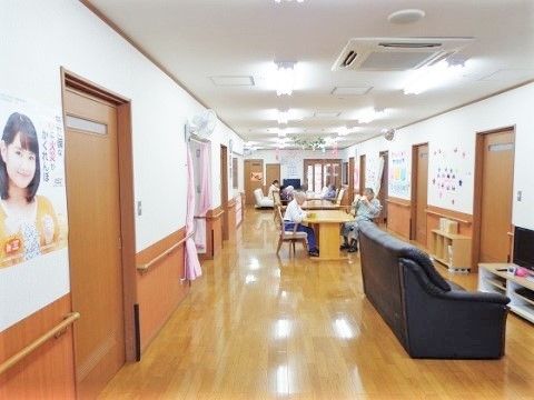 居室に面するスペースに入居者様が集う憩いの場を設けている。テーブルセットを備え、壁際に置いたテレビの前にソファを配置している。