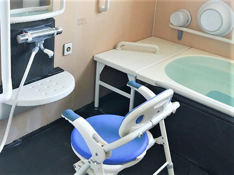 黒い床で青い浴用椅子の置かれたシャワースペースのある浴室