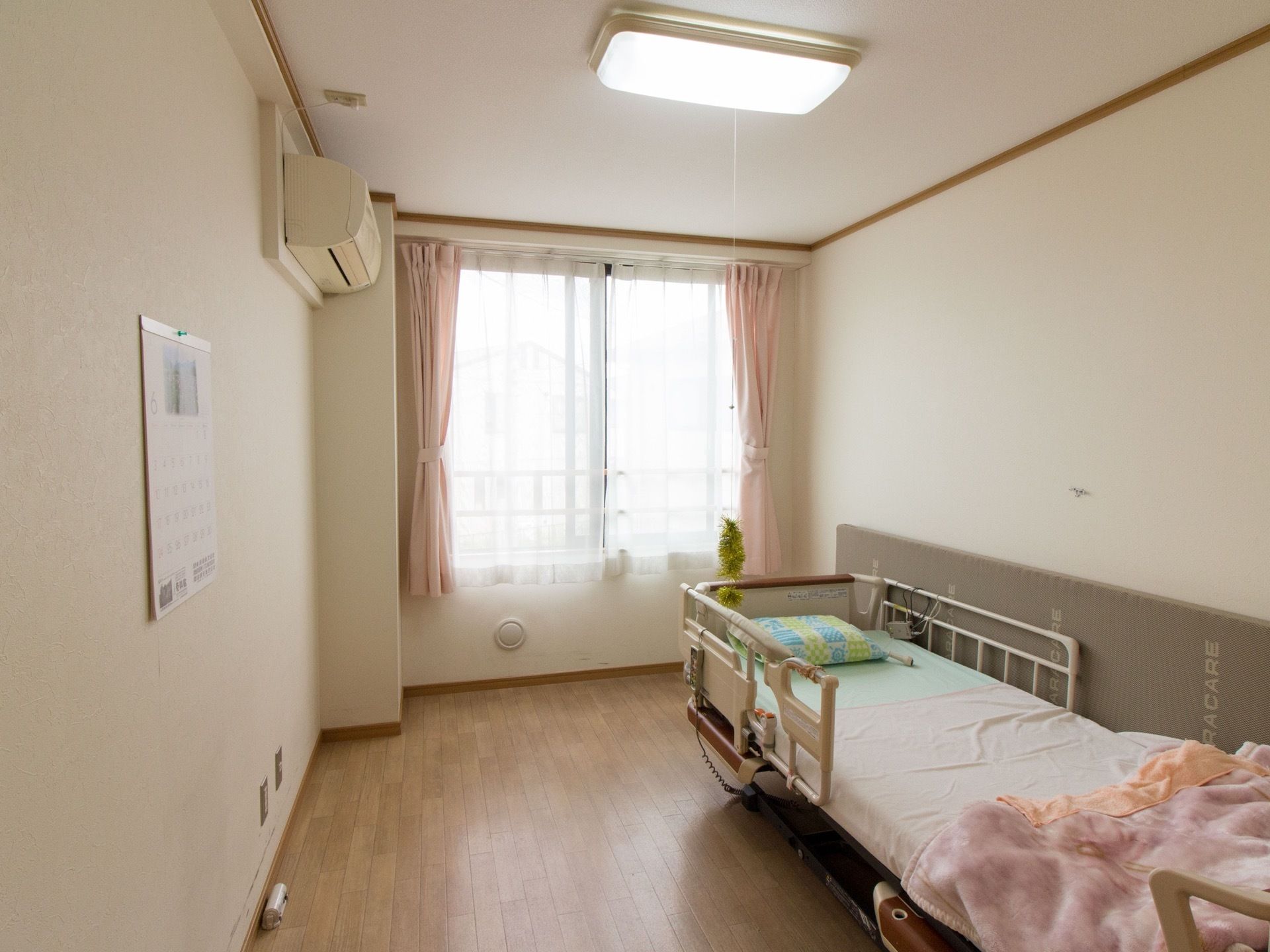 大きな窓から優しい日が差し込む。電動ベッド横の壁にはクッションが貼ってあり、安全性が高められている。